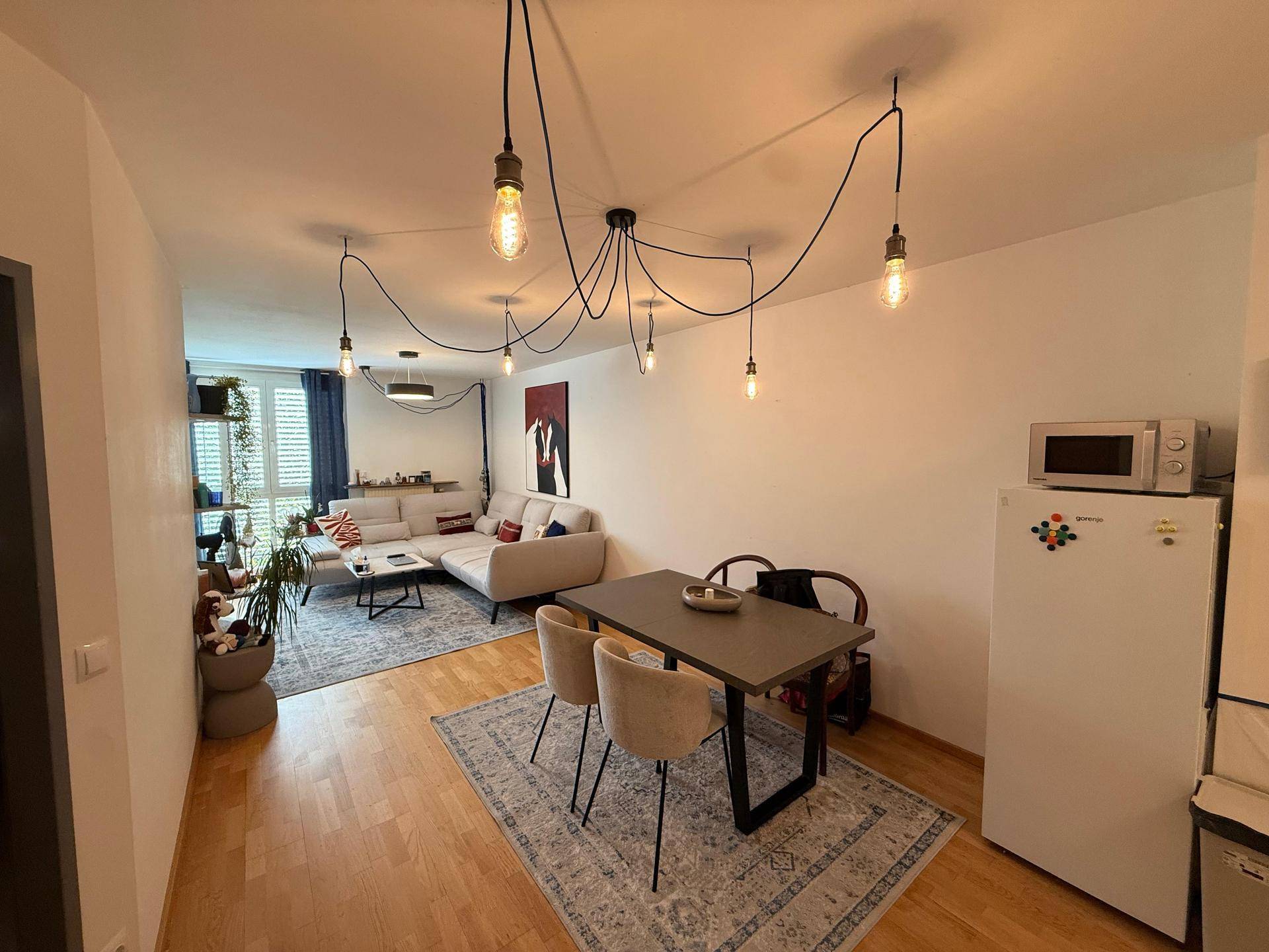 Heller Essbereich mit Holzboden, modernem Esstisch und Blick auf den angrenzenden Wohnbereich.