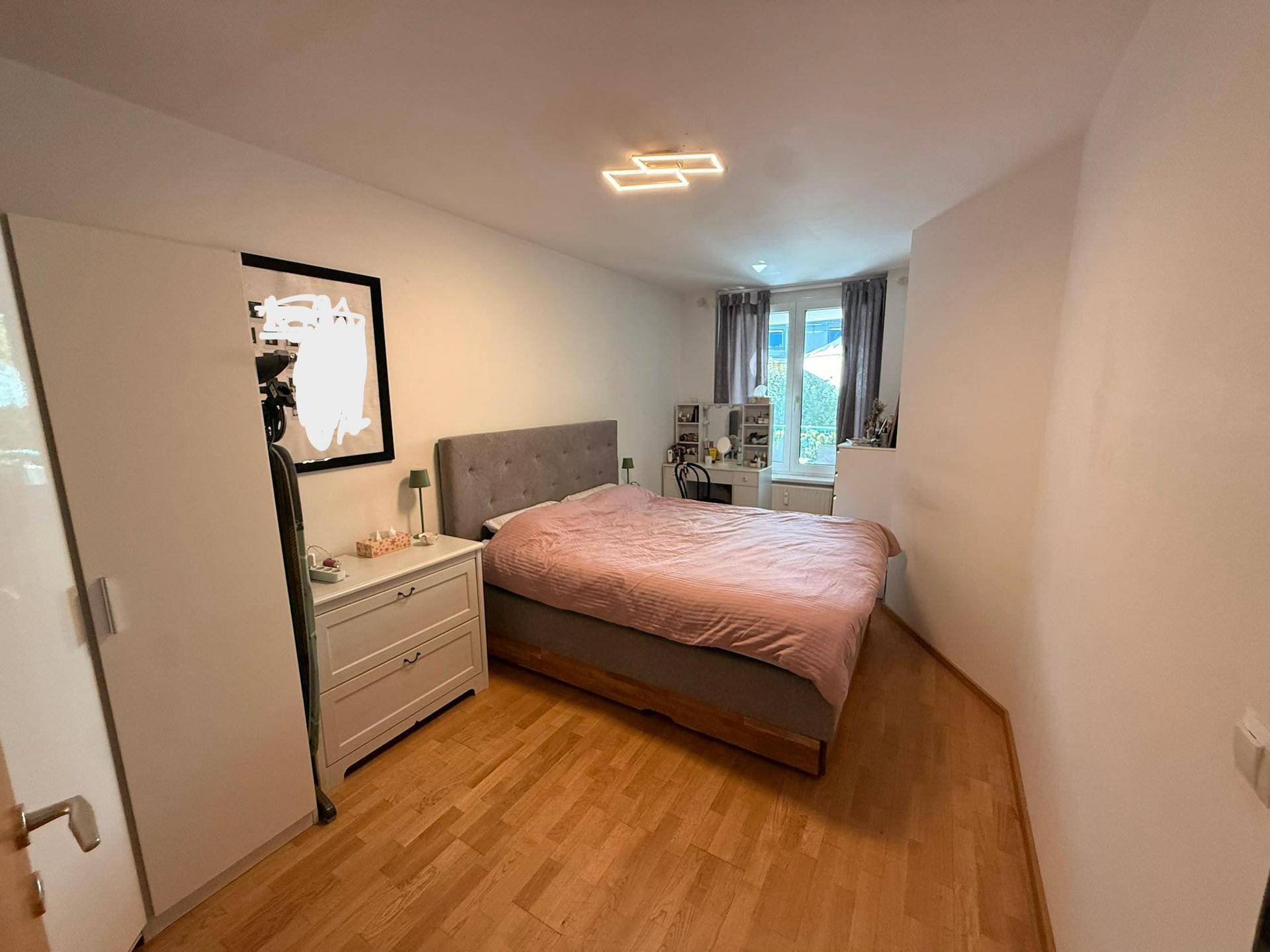 Gemütliches Schlafzimmer mit Doppelbett, Kommode und Holzboden, hell und einladend.