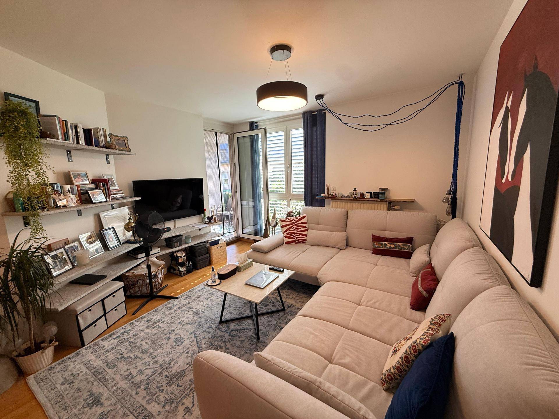 Gemütliches Wohnzimmer mit großem Ecksofa, Fernseher und direktem Zugang zum Balkon.