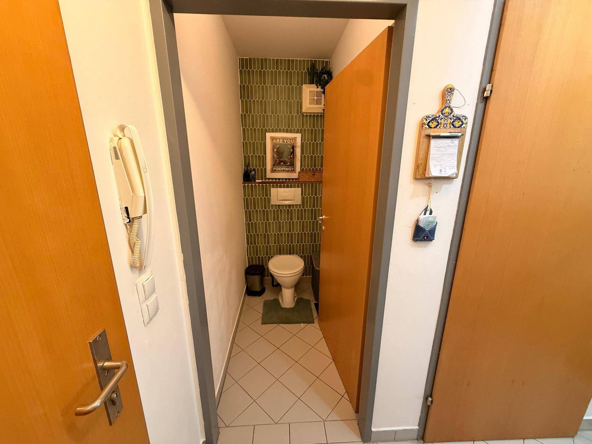 Kleines Gäste-WC mit grüner Akzentwand und schlichtem Design, funktional und sauber.