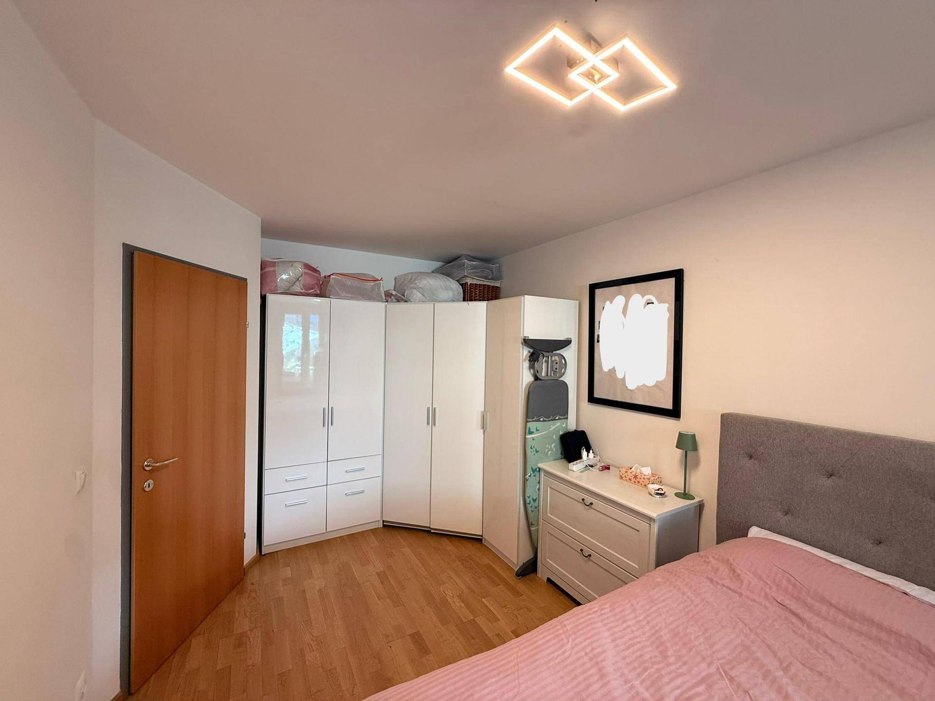 Helles Schlafzimmer mit Holzboden, großem Bett und praktischen Eckschränken für Kleidung.
