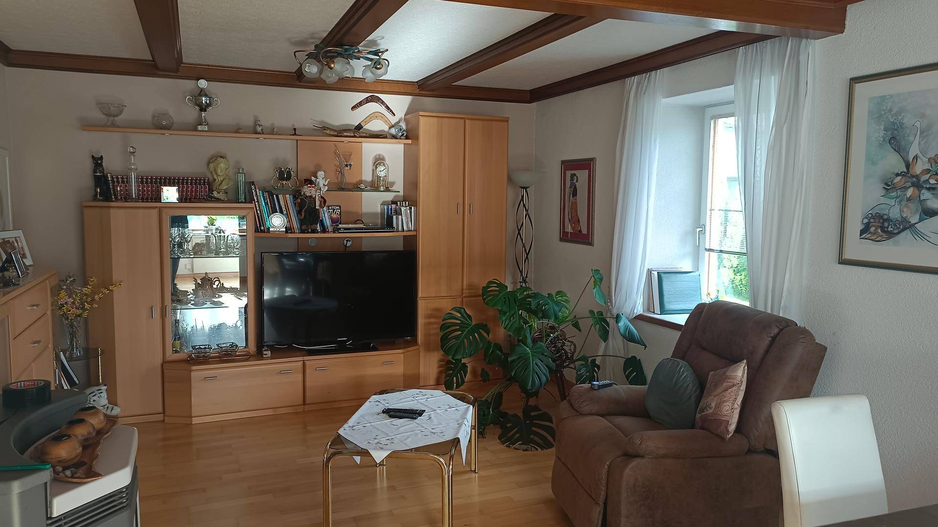 Wohnzimmer mit Holzbalkendecke, Parkettboden und gemütlicher Einrichtung.