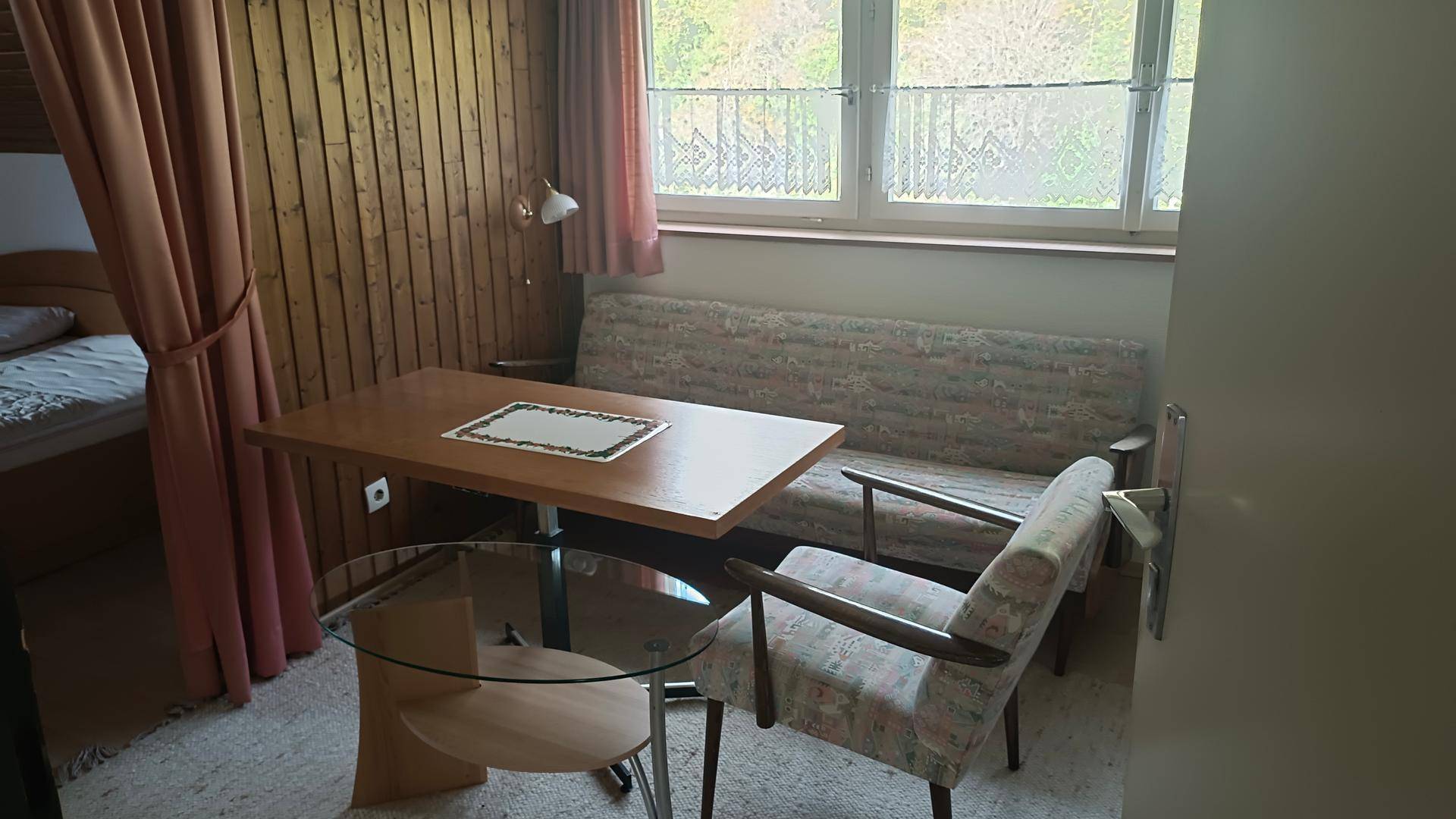 Rustikaler Wohnbereich mit Holzvertäfelung, Sofa und einem kleinen Esstisch.