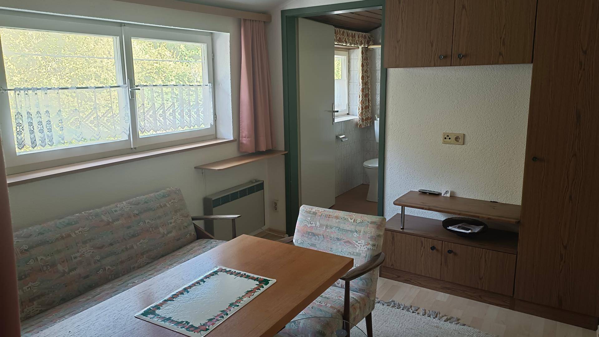 Gemütlicher Wohnbereich mit Sofa, Esstisch und Zugang zu einem Badezimmer.