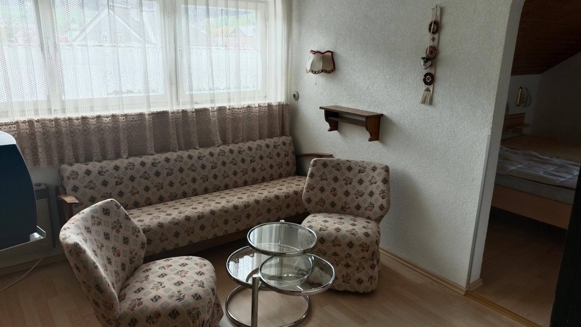 Heller Wohnbereich mit bequemen Sitzmöbeln, Couchtisch und Blick ins Schlafzimmer.