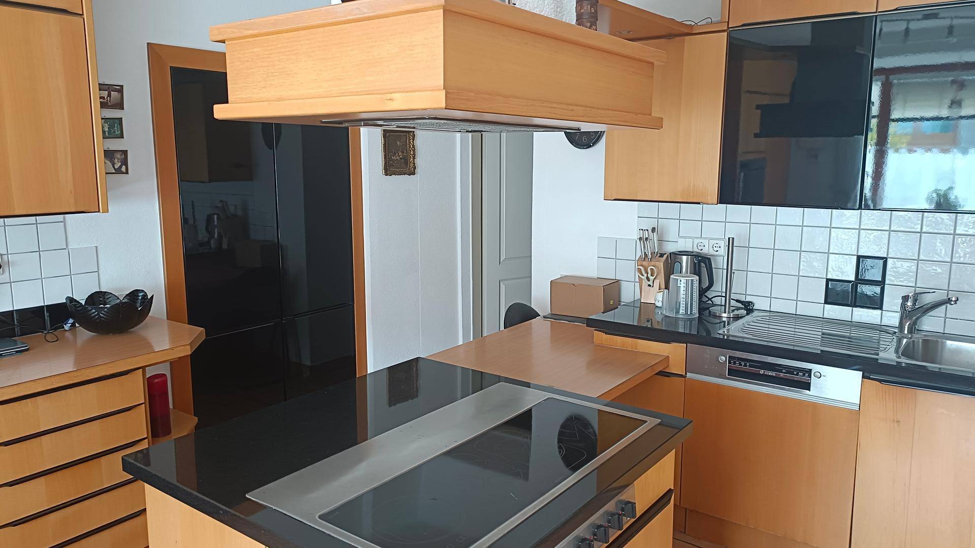Funktionale Küche mit Holzelementen, Kochinsel und integrierten Geräten.