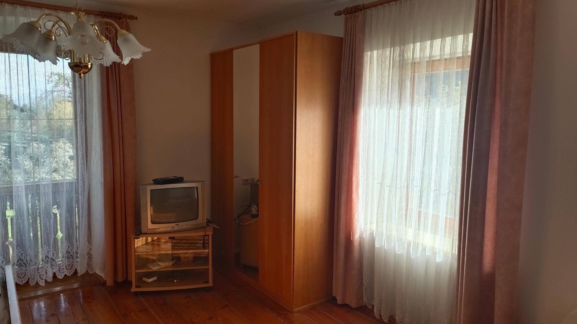 Schlafzimmer mit Holzboden, Kleiderschrank und Zugang zu einem französischen Balkon.