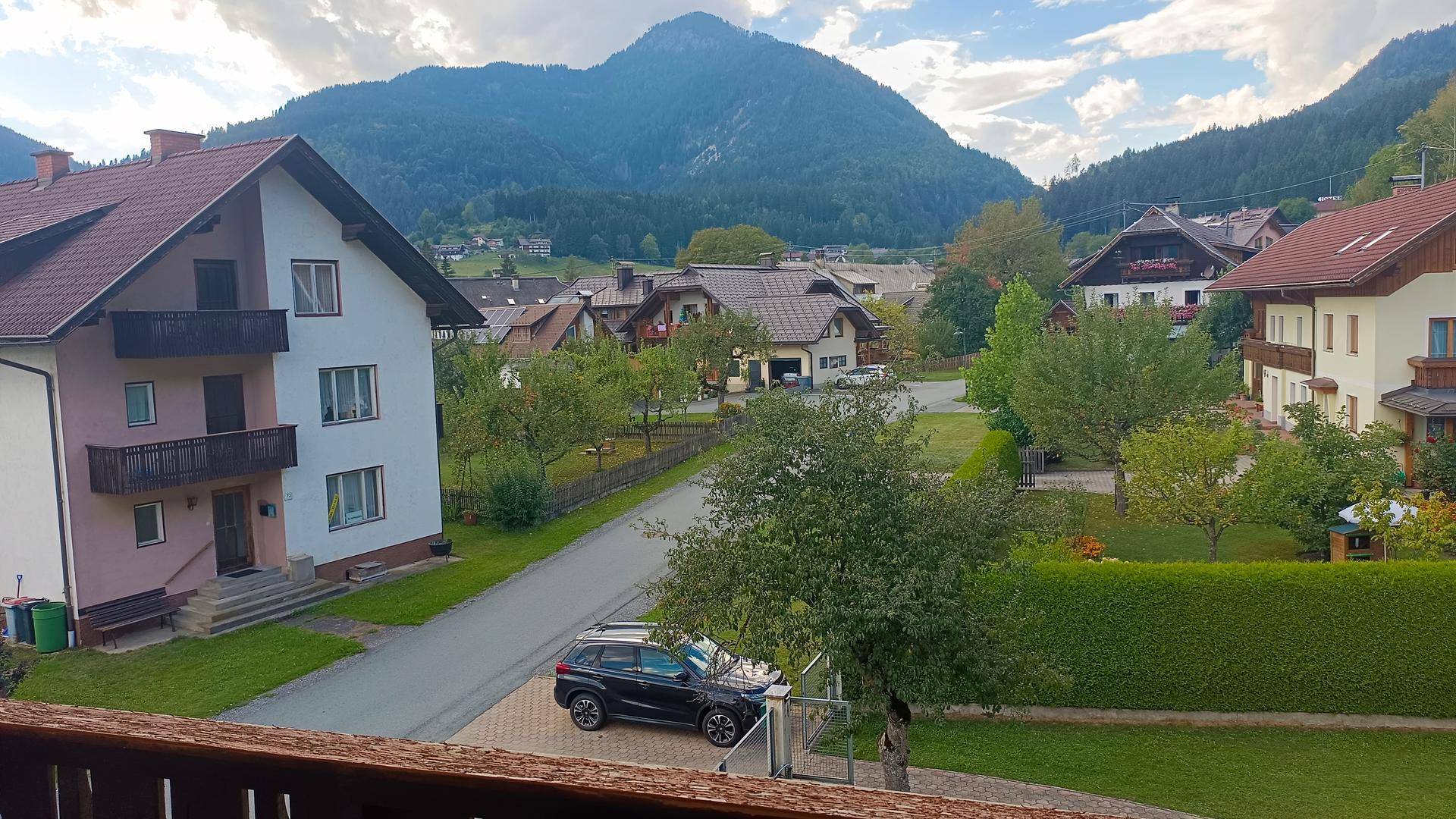 Panoramablick auf die umliegende Wohngegend mit Häusern, Gärten und majestätischen Bergen im Hintergrund.