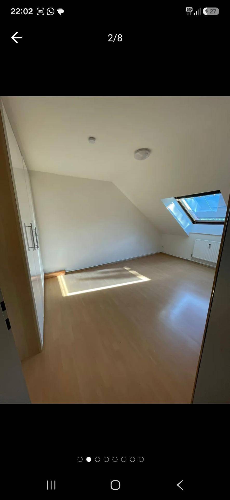 Helles Dachgeschosszimmer mit Holzfußboden, Einbauschrank und einem Dachfenster für viel Tageslicht.