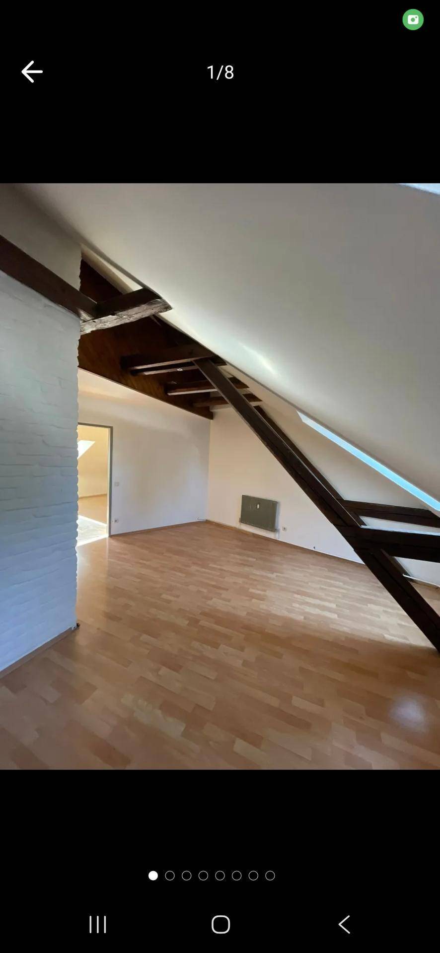 Geräumiger Dachgeschoss-Wohnbereich mit sichtbaren Holzbalken und hellem Holzfußboden.