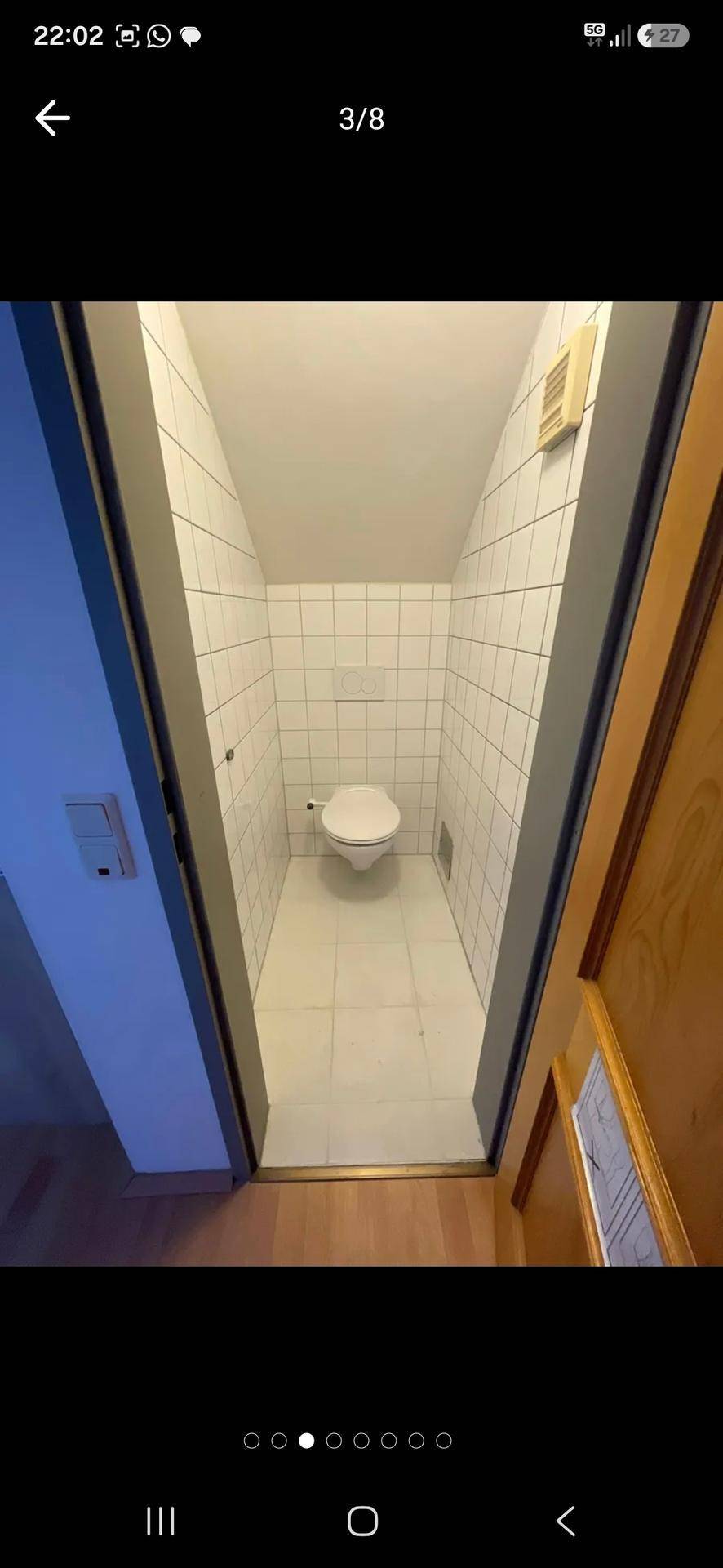 Schmale Gästetoilette mit weißen Fliesen und wandhängendem WC im Dachgeschoss.