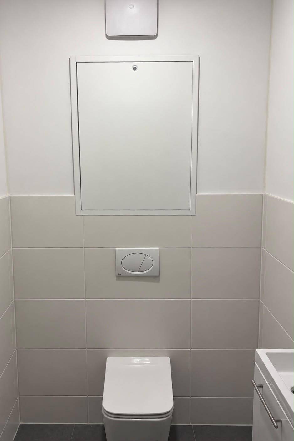Modernes Gäste-WC mit wandhängender Toilette, kleinem Waschbecken und hellen Fliesen.