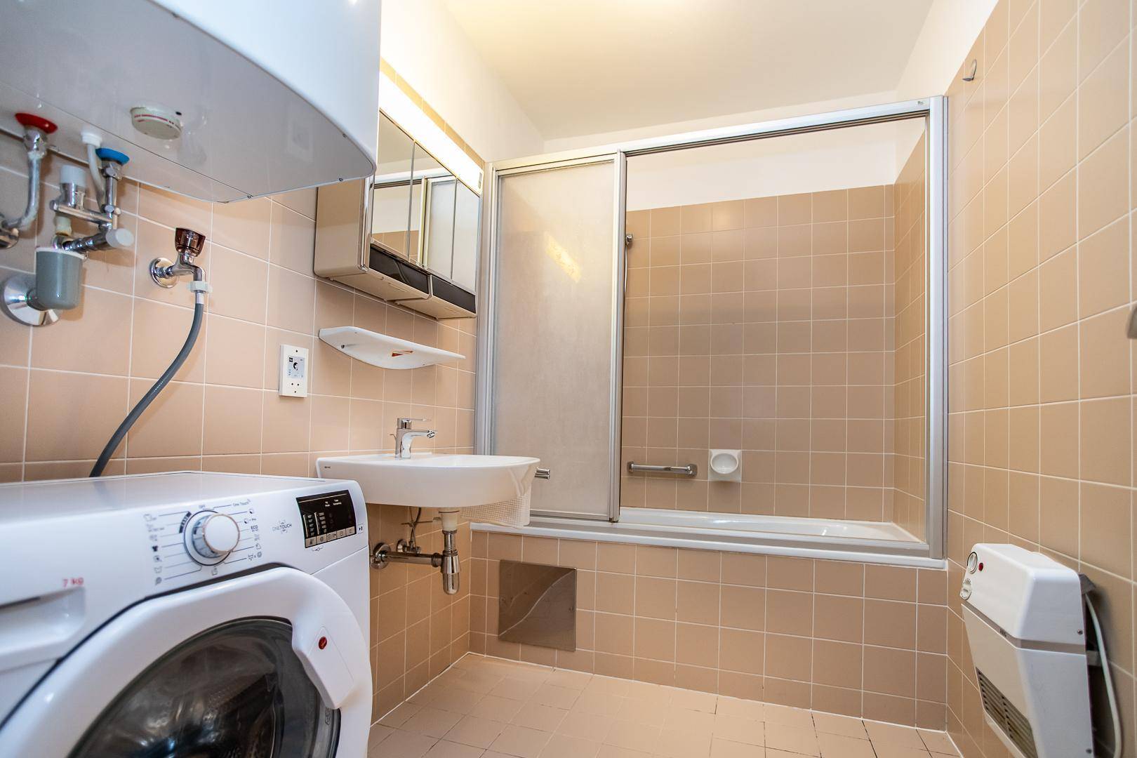 Funktionales Badezimmer mit Badewanne, Duschwand, Waschbecken und Waschmaschine.