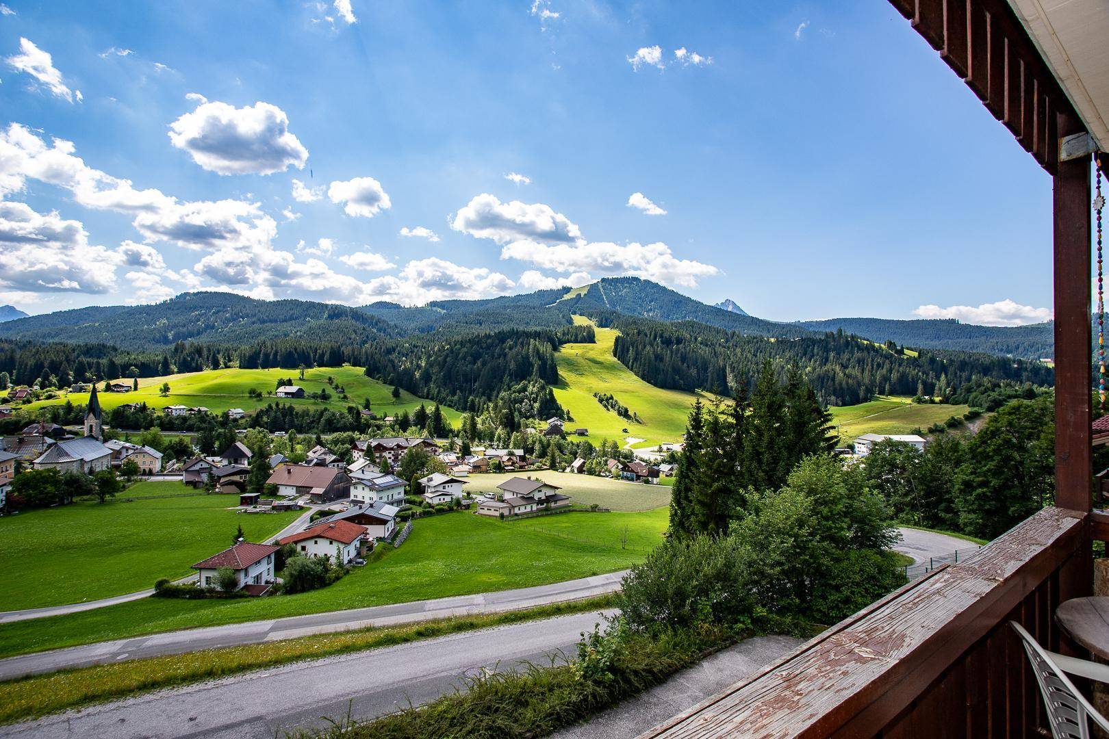 Panoramablick vom Balkon auf die idyllische Landschaft mit Bergen und Dorf.