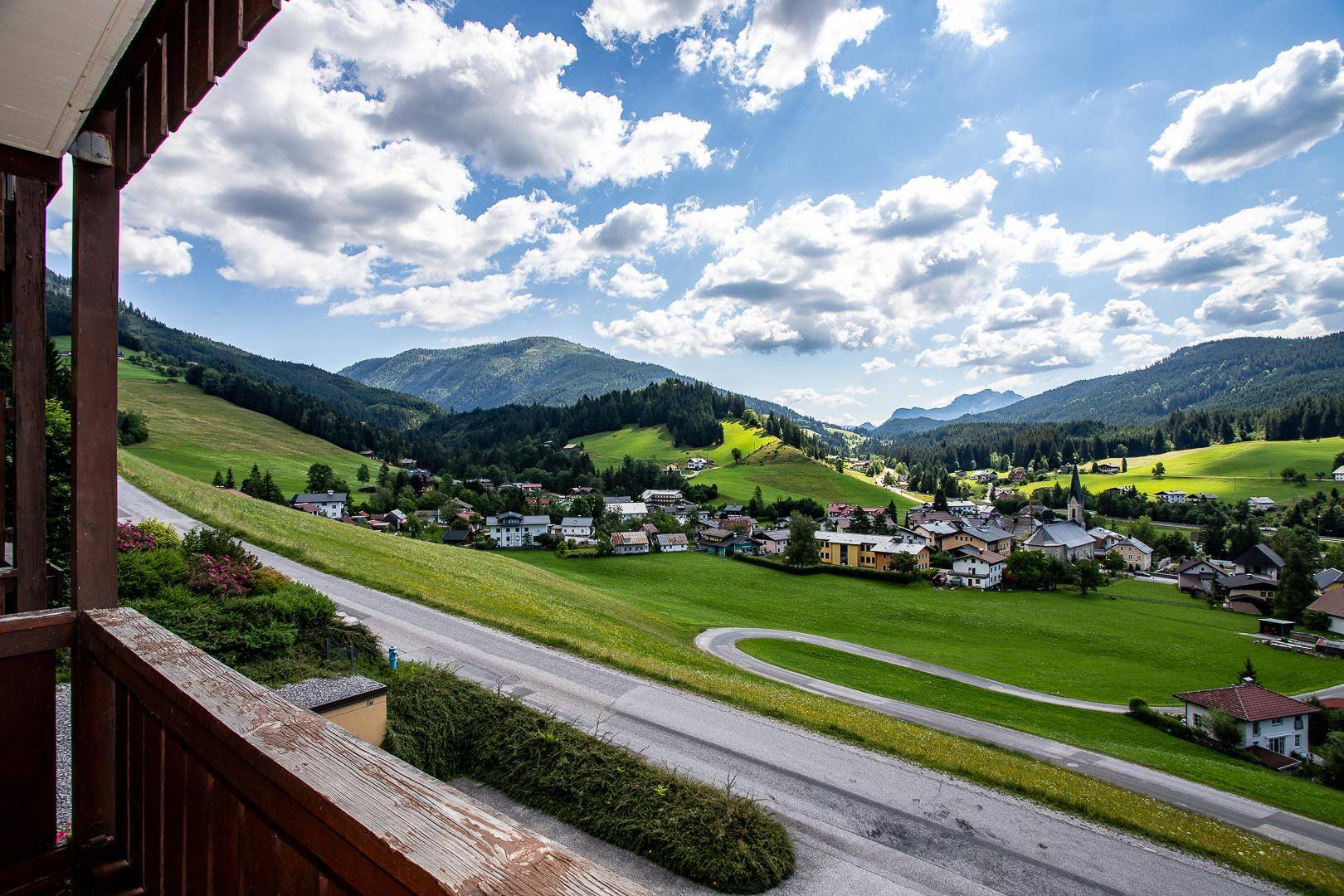 Weiter Blick vom Balkon über die kurvige Straße und das charmante Dorf im Tal.