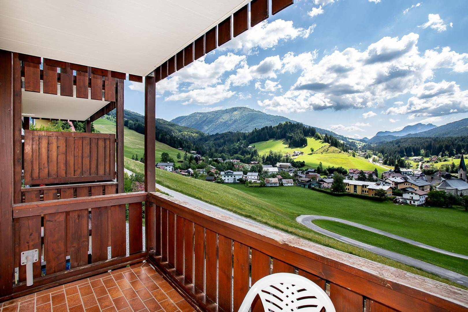 Sonniger Balkon mit Terrakottafliesen und weitem Blick über das grüne Tal.