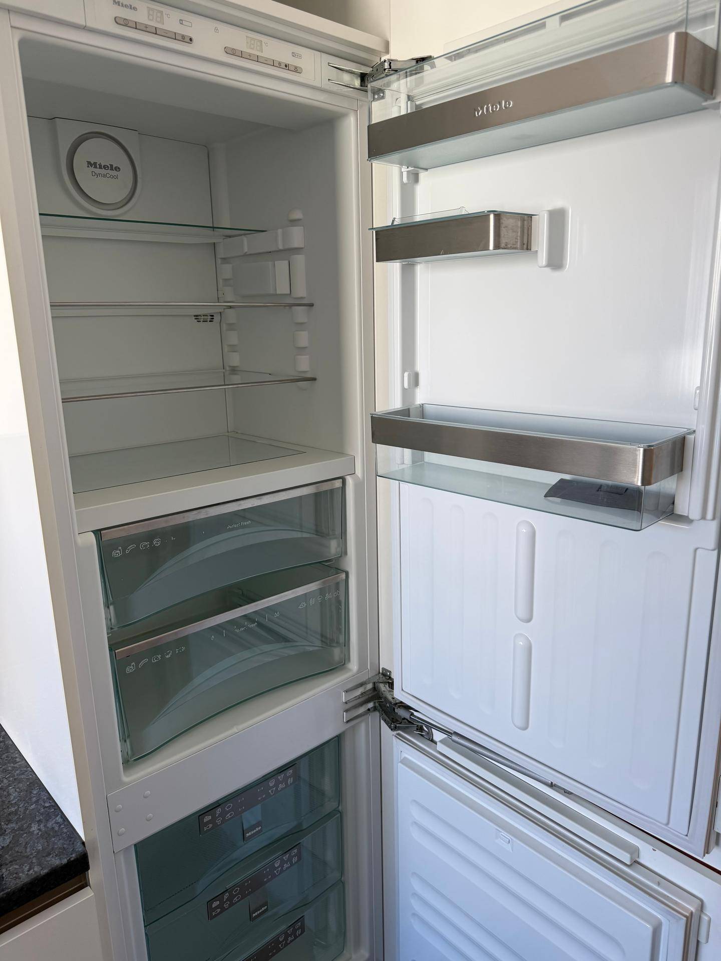 Offener Miele-Kühlschrank mit mehreren Fächern und Schubladen für Lebensmittel.