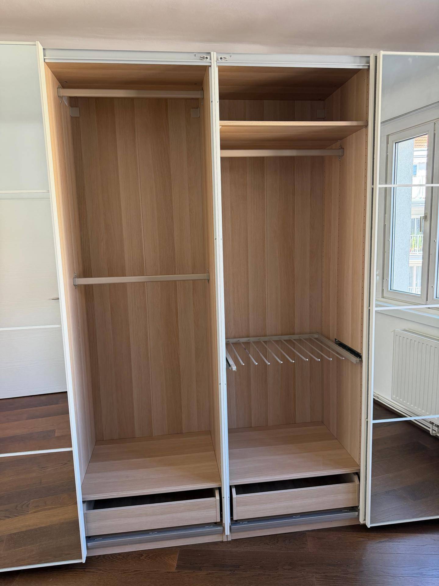 Innenansicht eines Kleiderschranks mit Kleiderstangen, Regalen und Schubladen für Stauraum.