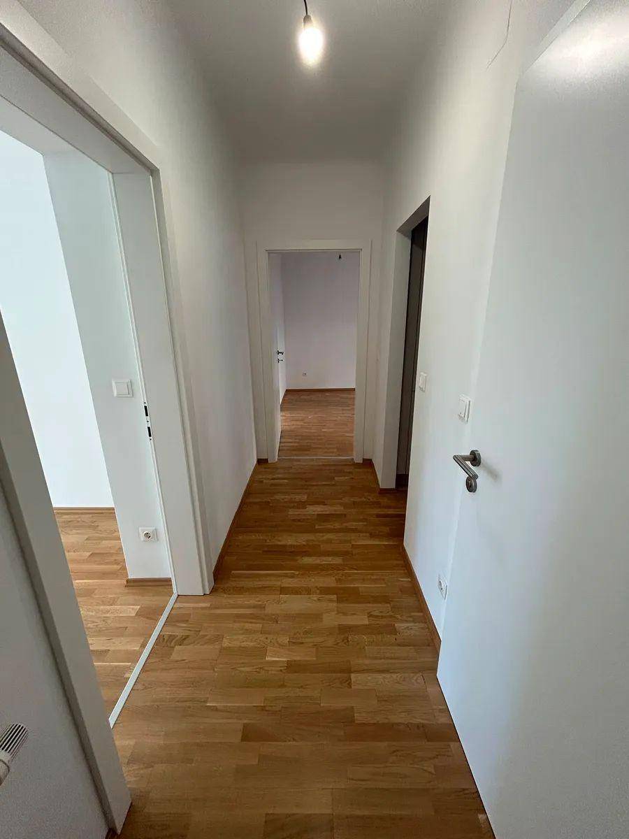 Heller Flur mit Parkettboden, der zu verschiedenen Zimmern der Wohnung führt.