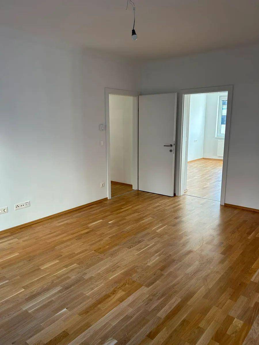 Geräumiges Zimmer mit Holzboden und Zugang zu weiteren Räumen, ideal für flexible Nutzung.