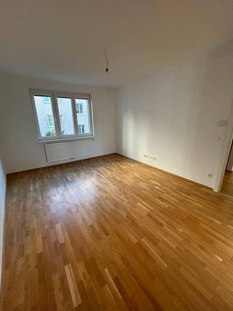 Gemütliches Zimmer mit Parkettboden und einem Fenster, das den Raum mit Licht füllt.
