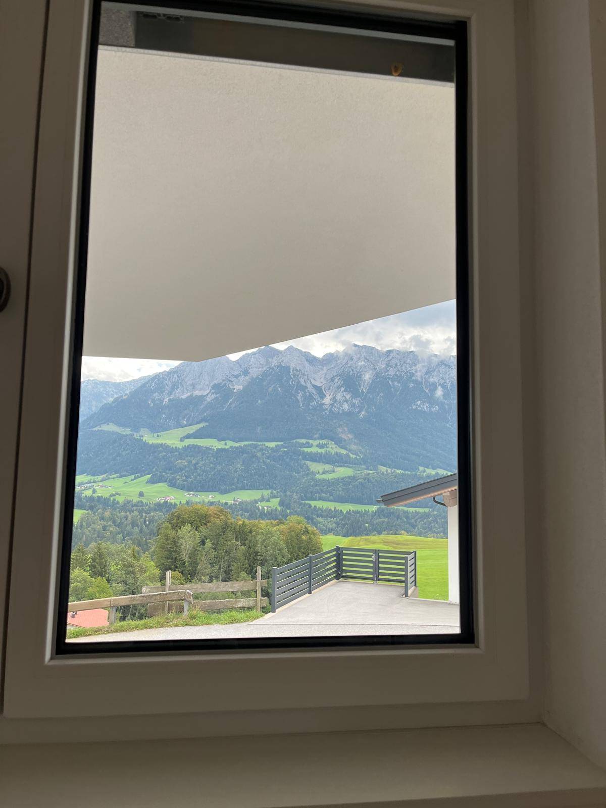 Malerischer Ausblick aus dem Fenster auf die umliegende Berglandschaft und grüne Wiesen.
