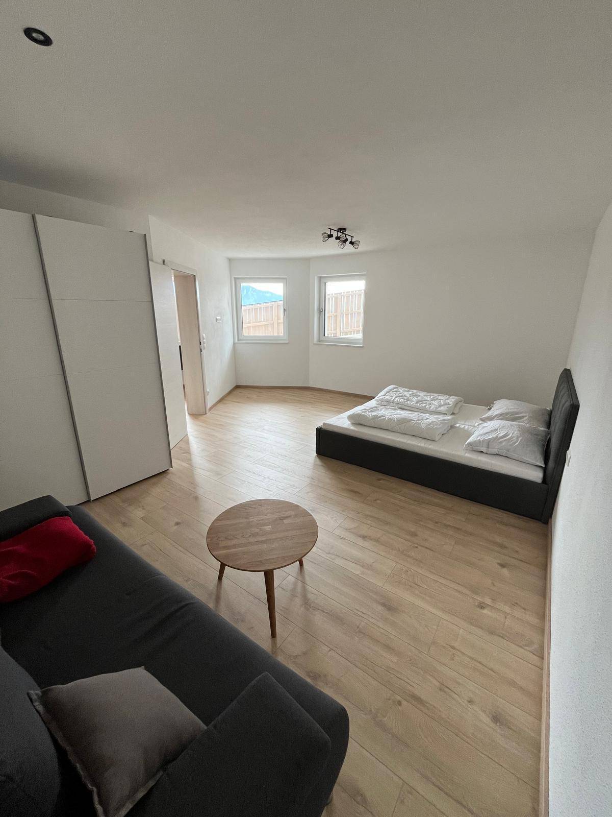Schlafzimmer mit Doppelbett, Sofa, Beistelltisch und weißen Einbauschränken, bietet viel Stauraum.
