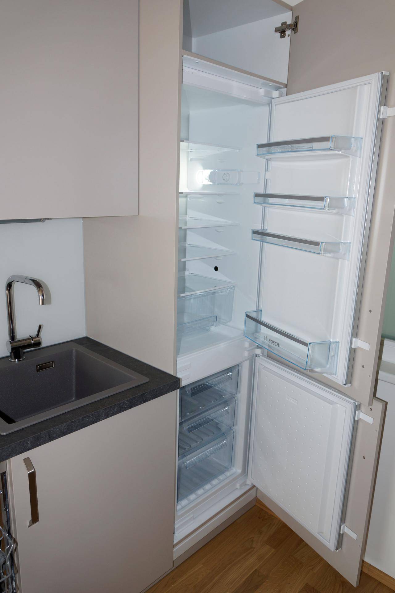 Integrierter Kühlschrank mit Gefrierfach, offen gezeigt, neben der Küchenspüle.