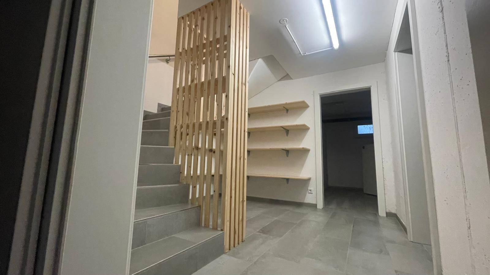 Kellerbereich mit gefliester Treppe, Holzabtrennung und praktischen Wandregalen.