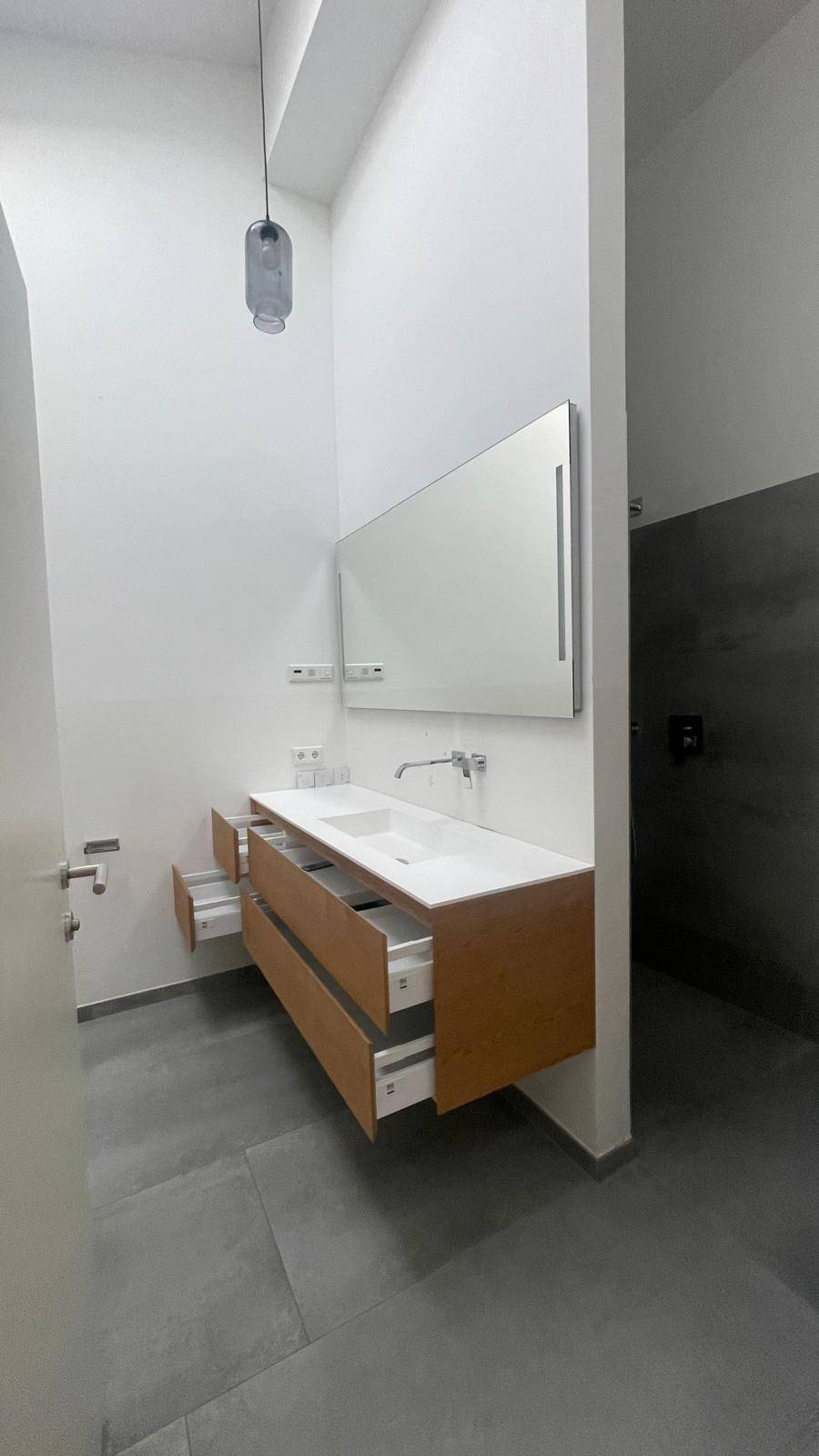 Modernes Badezimmer mit Doppelwaschbecken, Holzunterschrank und großem Spiegel.