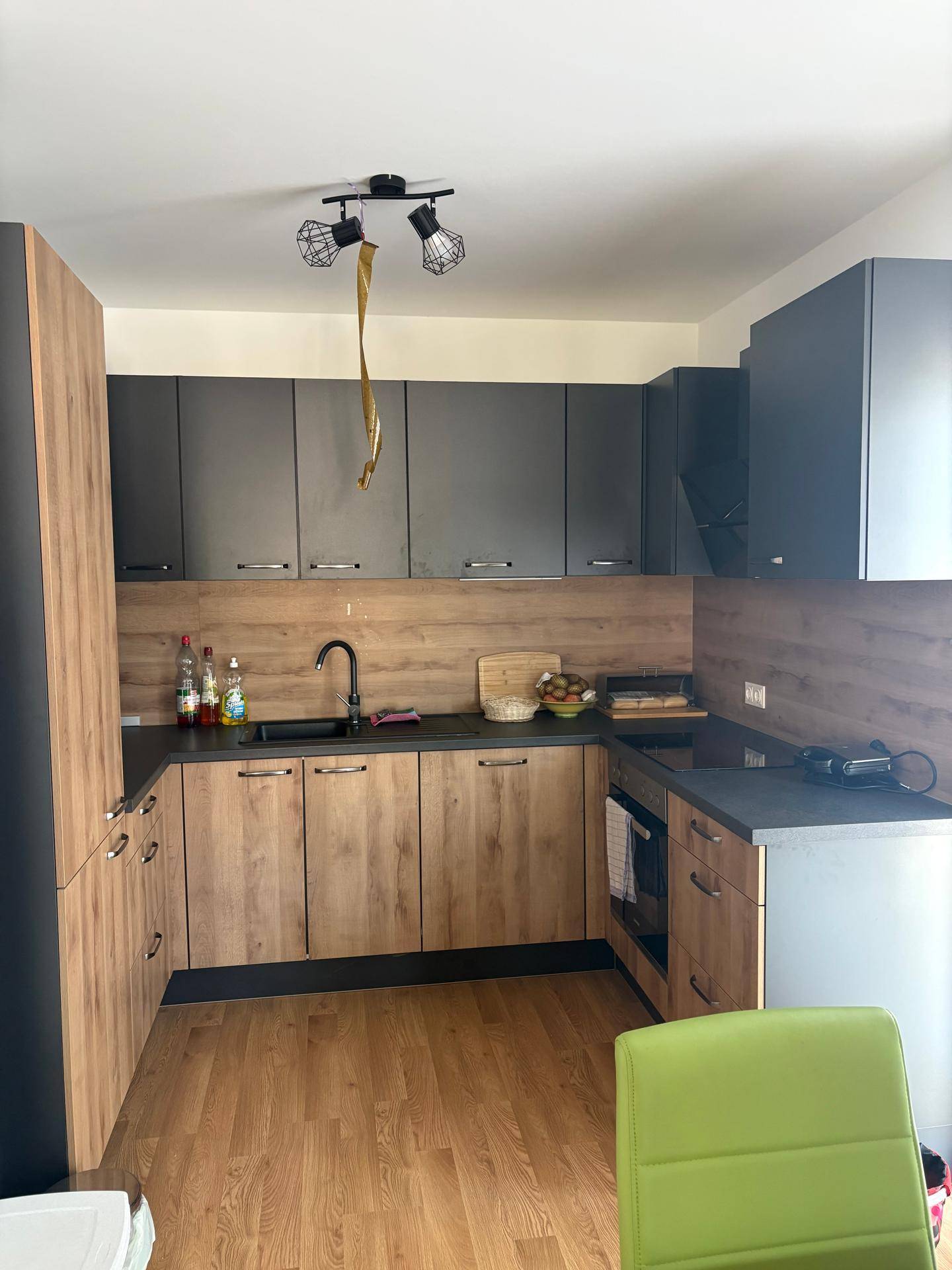 Moderne Küche mit dunklen Oberschränken und Holzoptik-Unterschränken, ausgestattet mit Spüle und Arbeitsplatte.