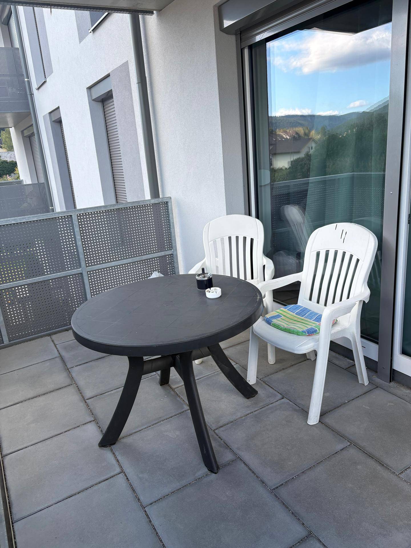 Balkon mit Tisch und Stühlen, ideal für entspannte Stunden im Freien mit Blick auf die Umgebung.