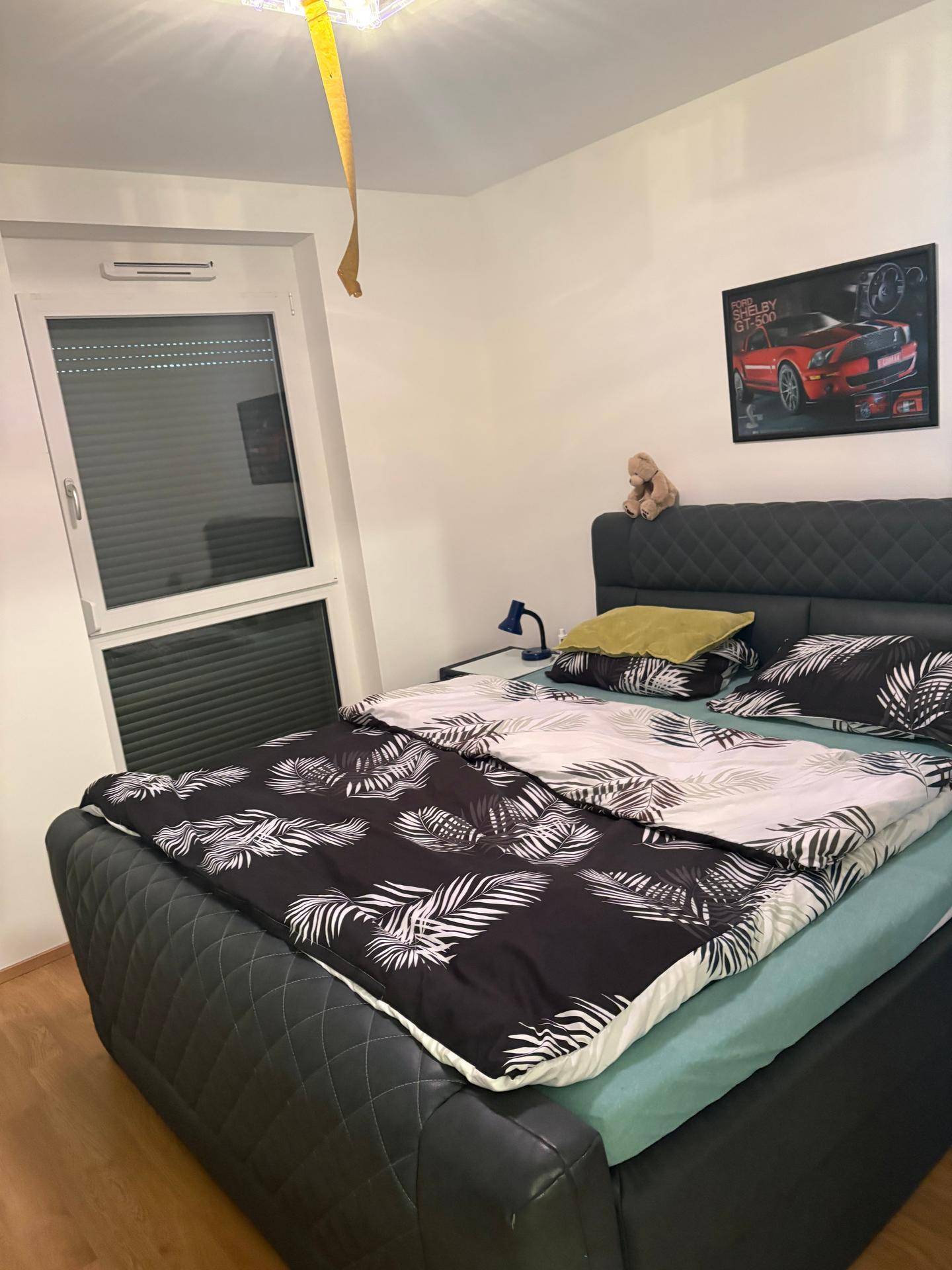 Gemütliches Schlafzimmer mit modernem Bett und dekorativem Wandbild, bietet eine angenehme Atmosphäre.