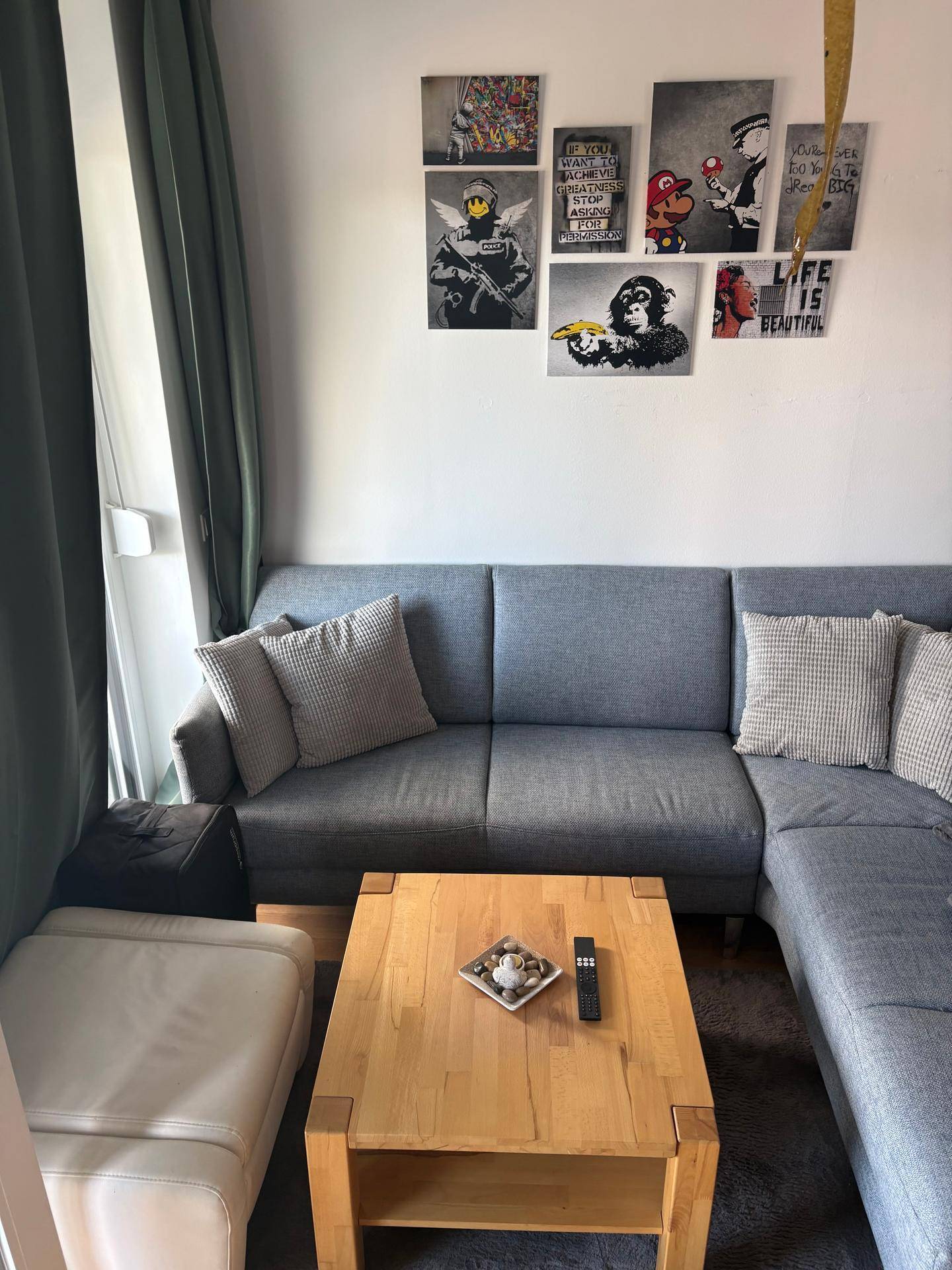 Gemütliches Wohnzimmer mit grauem Ecksofa und modernem Couchtisch, dekoriert mit Wandbildern.
