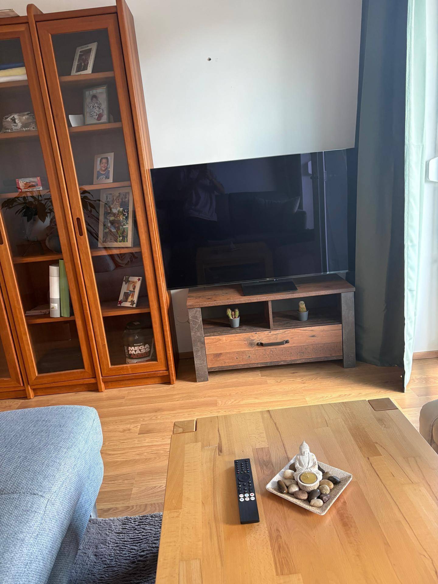 Detailansicht des Wohnzimmers mit Holzvitrinen, Fernseher und Couchtisch, schafft eine wohnliche Atmosphäre.