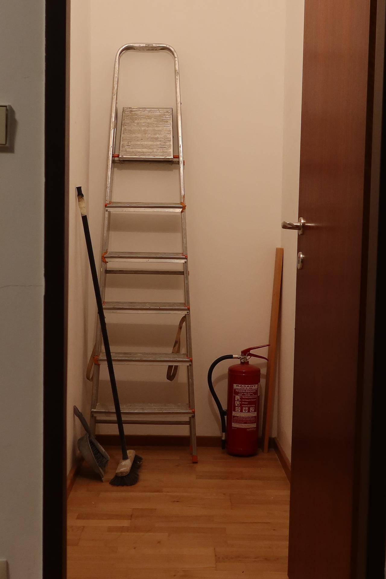 Praktischer Abstellraum mit Leiter und Feuerlöscher für Haushaltsutensilien.