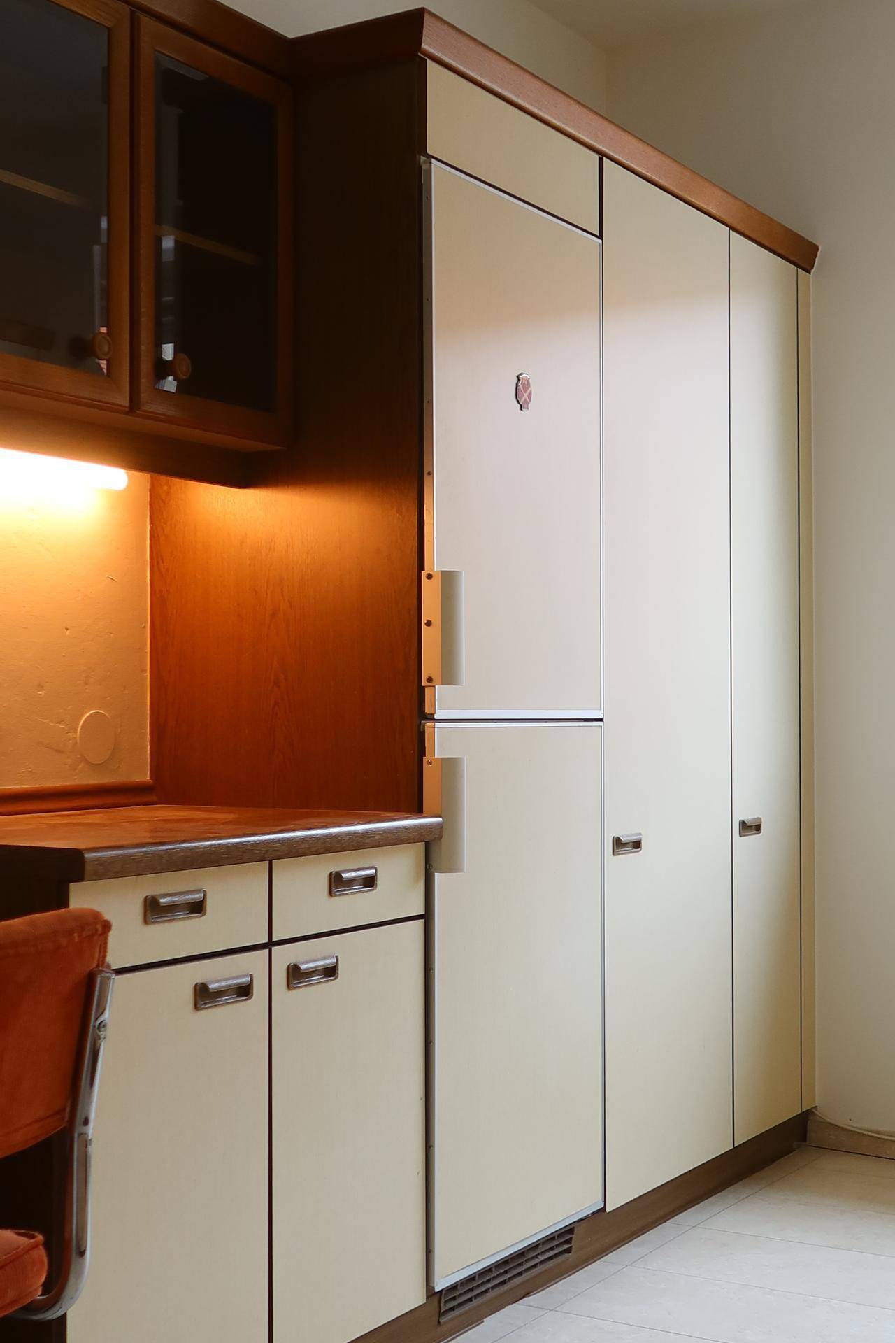 Küchenzeile mit integriertem Kühlschrank und weiteren Einbauschränken in hellem Holzton.