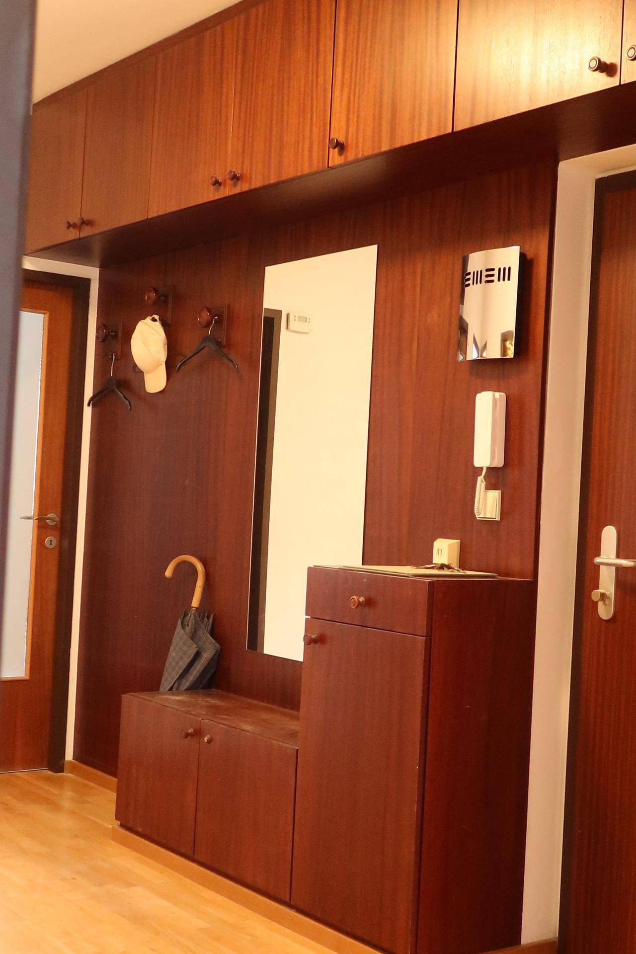 Flur mit Einbauschränken aus Holz, einem Spiegel und Garderobenhaken.