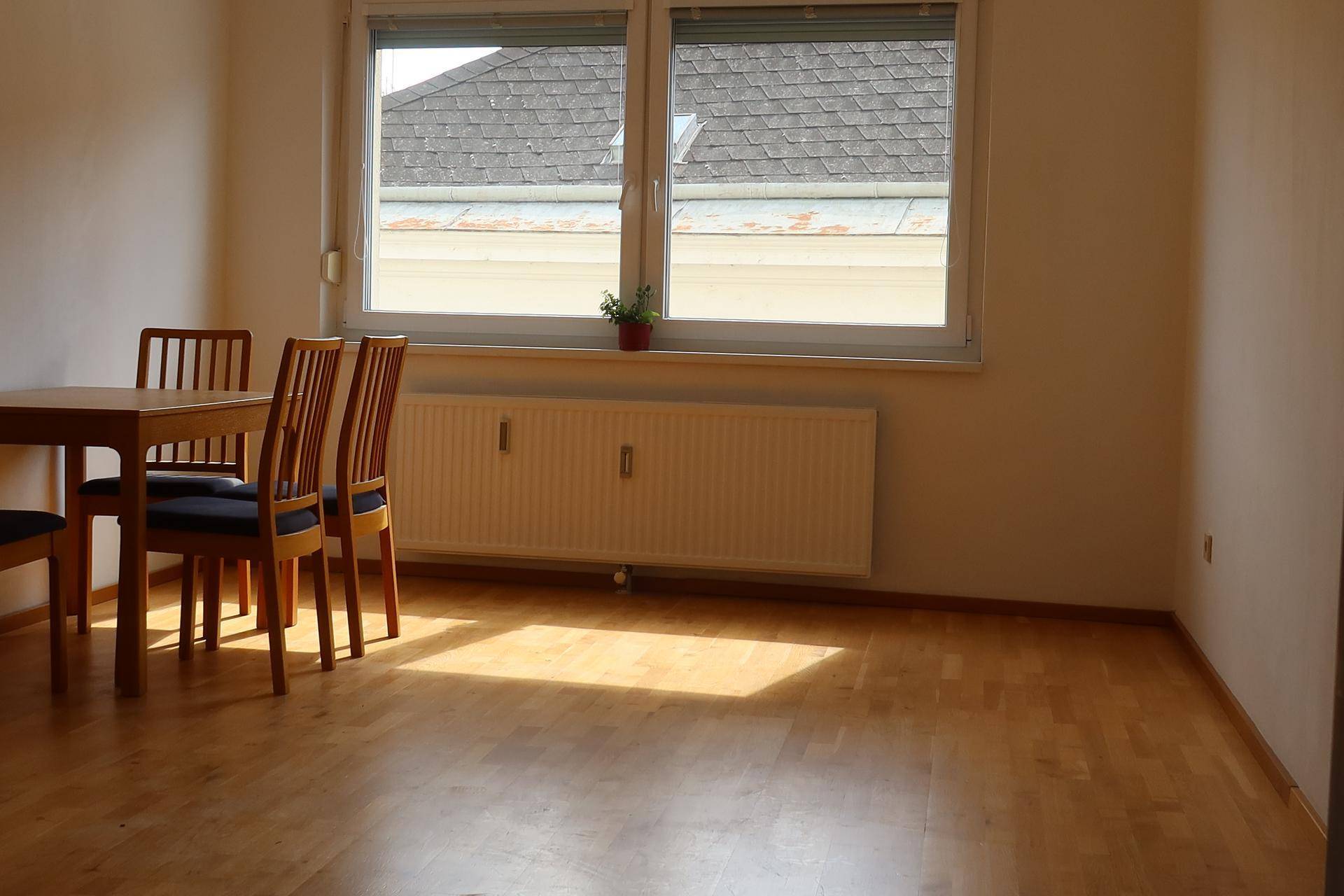 Heller Essbereich mit Holzboden und einem Fenster, das einen Blick auf die Dächer bietet.