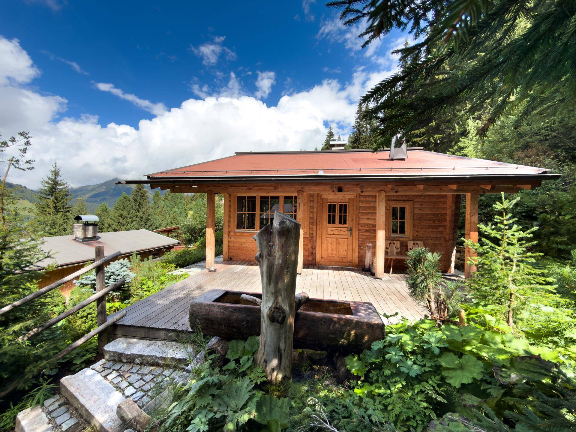 Idyllisches Holzchalet mit großer Holzterrasse und Blick auf die umliegende Berglandschaft.