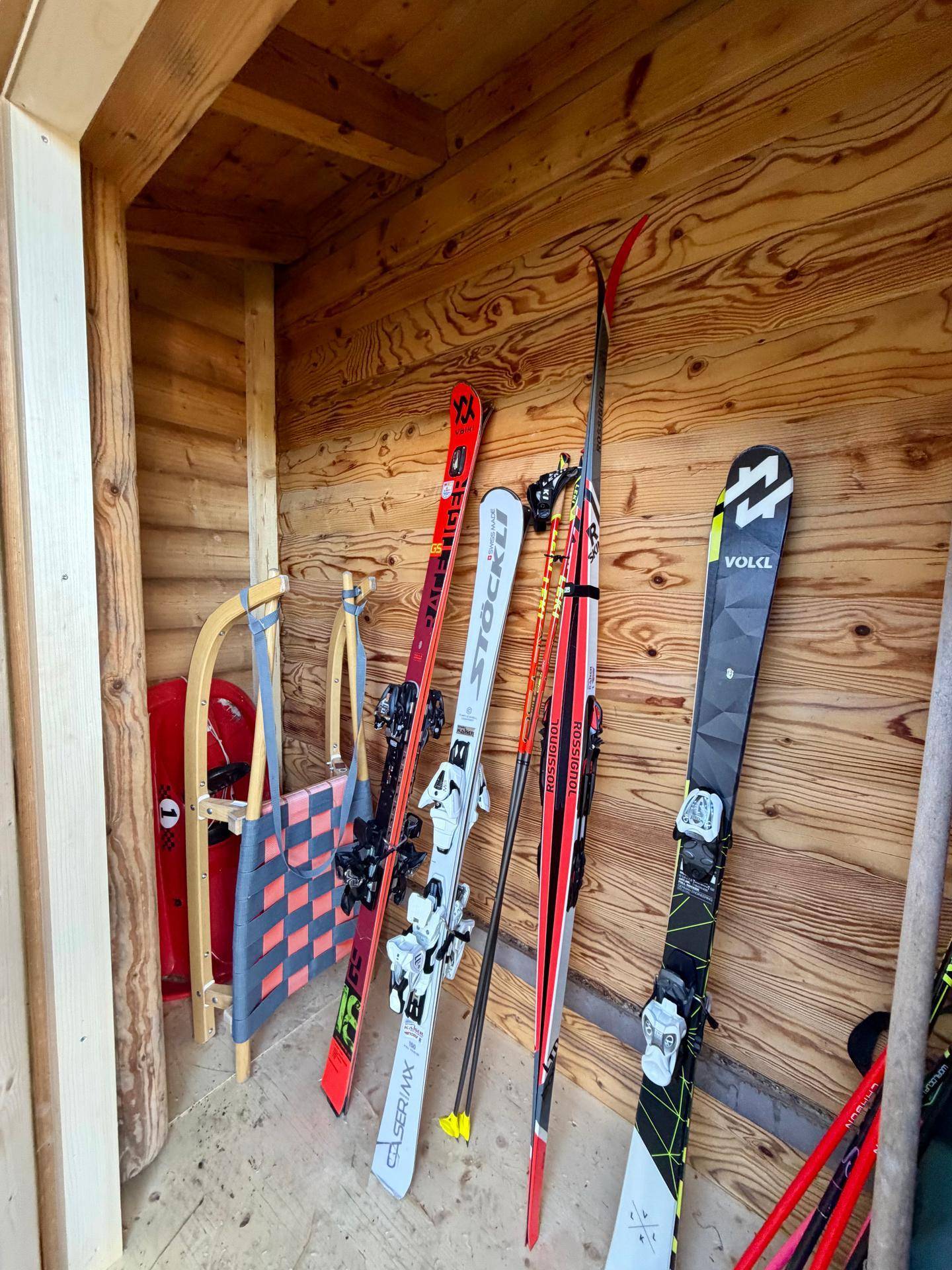 Praktischer Abstellraum mit Holzwänden zur Aufbewahrung von Skiern und Wintersportgeräten.