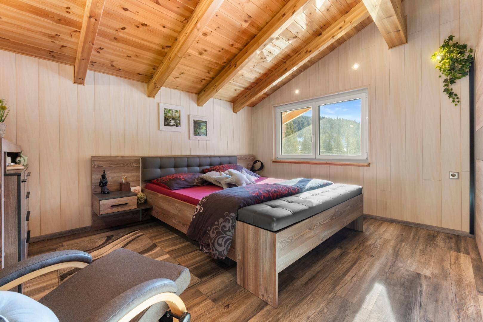 Helles Schlafzimmer mit Holzdachschrägen, Holzboden und einem bequemen Doppelbett.