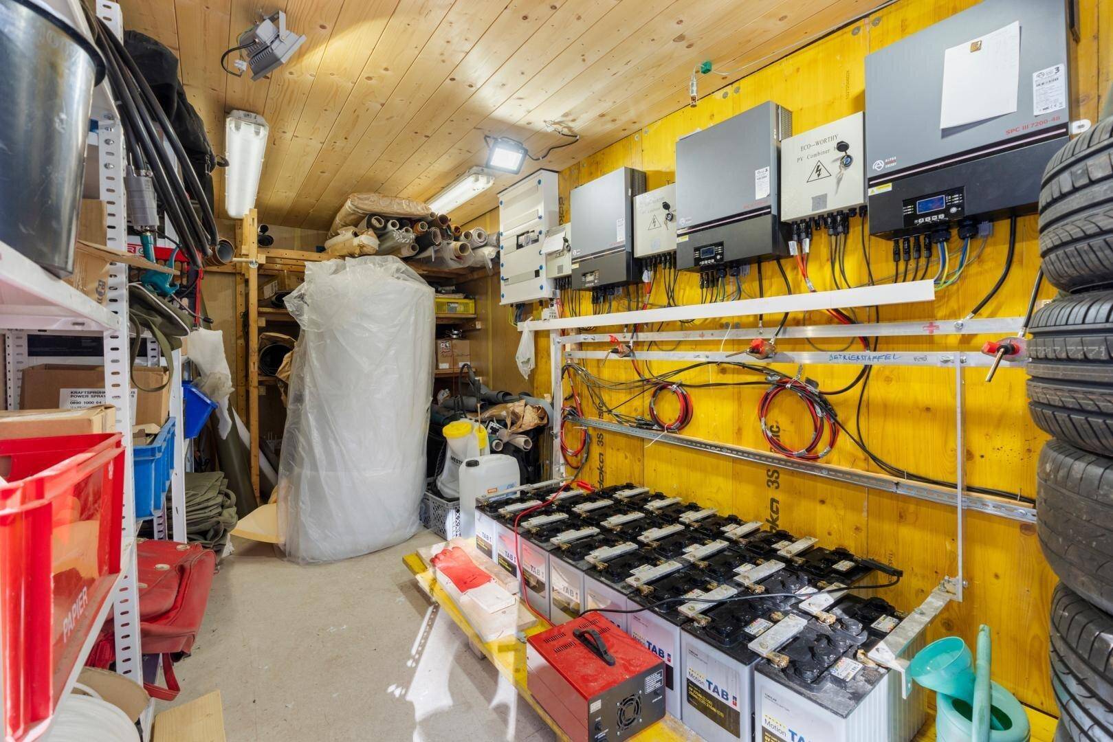 Technikraum mit Solaranlagen-Wechselrichtern, Batterien und Reifenlagerung.