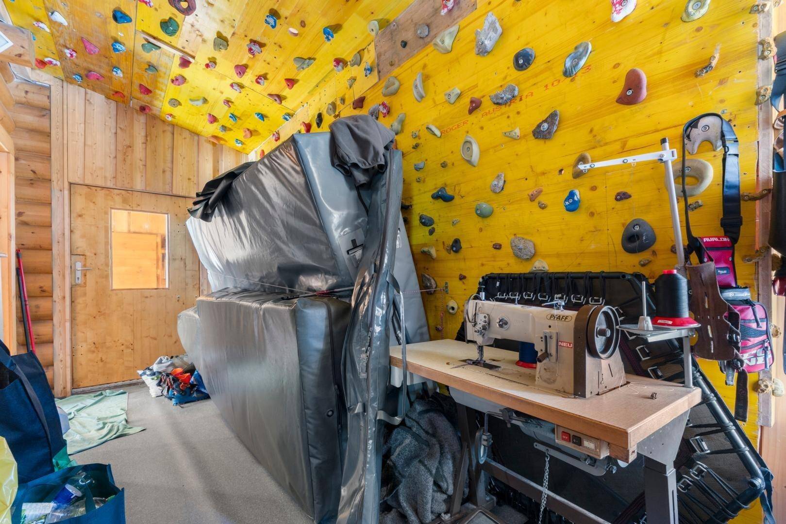 Hobbyraum mit Kletterwand, Nähmaschine und Matten für sportliche Aktivitäten.