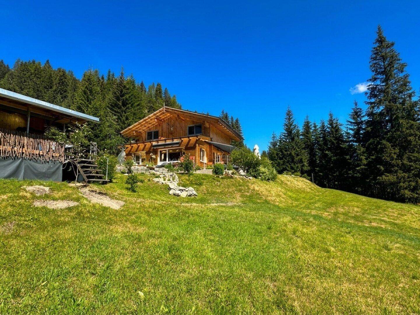 Weitläufiges Grundstück mit Blockhaus, Nebengebäude und unberührter Natur in den Alpen.