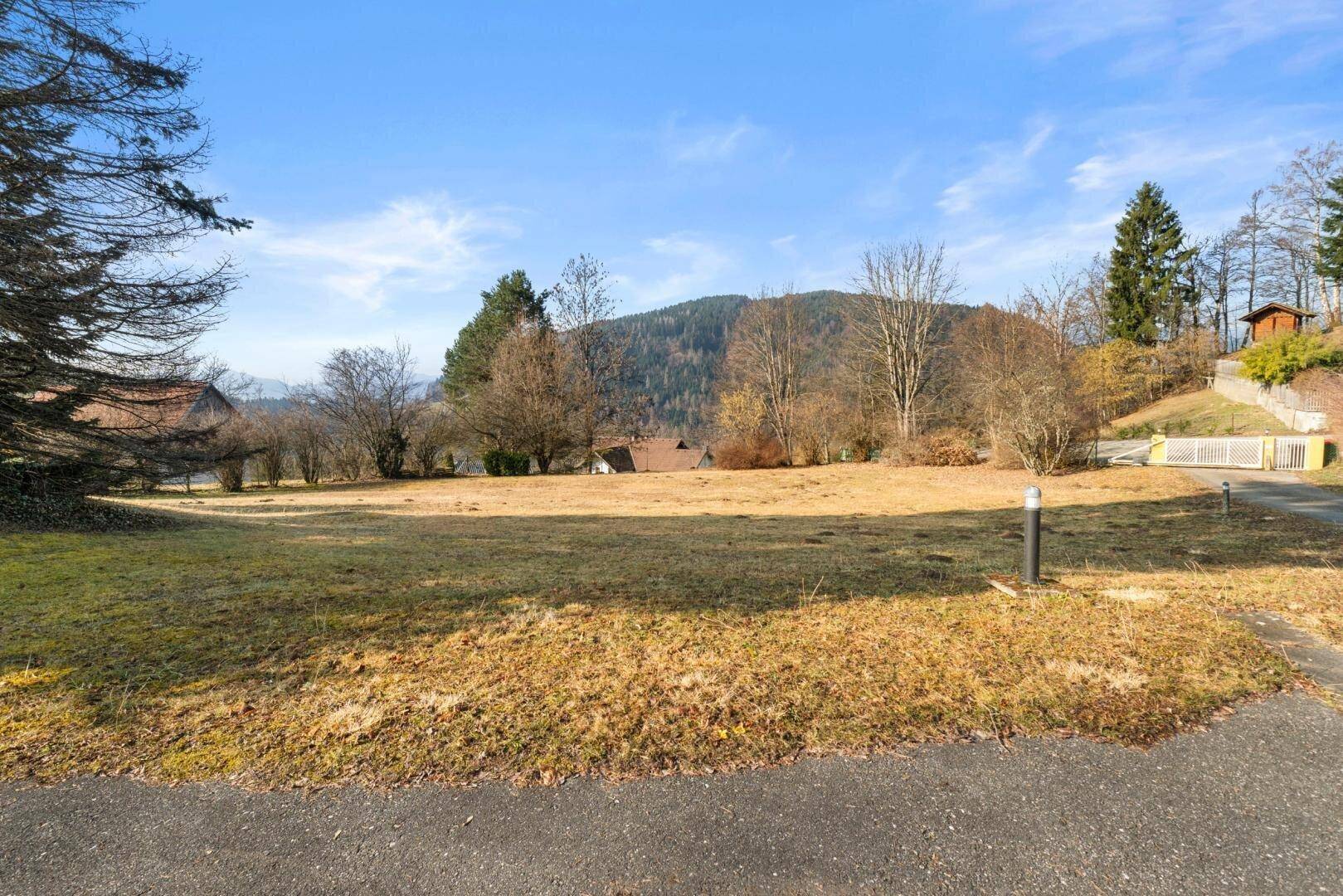 Weitläufige Rasenfläche des Gartens mit Blick auf die Berge und umliegende Häuser.