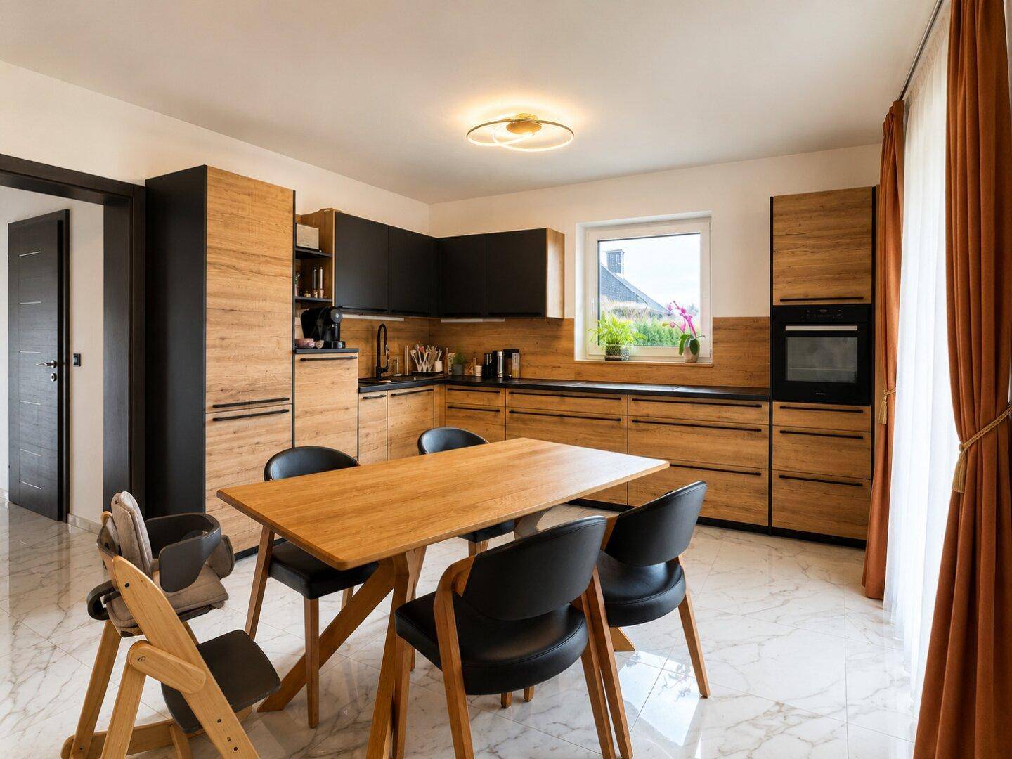 Moderne Einbauküche mit Holzfronten, schwarzem Akzent und Essbereich, hell und funktional.
