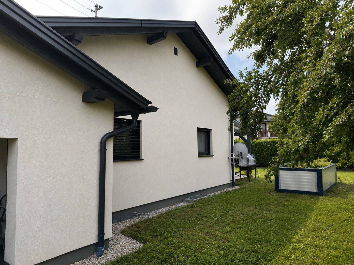 Seitenansicht des Hauses mit schlichter Fassade und angrenzendem Gartenbereich.