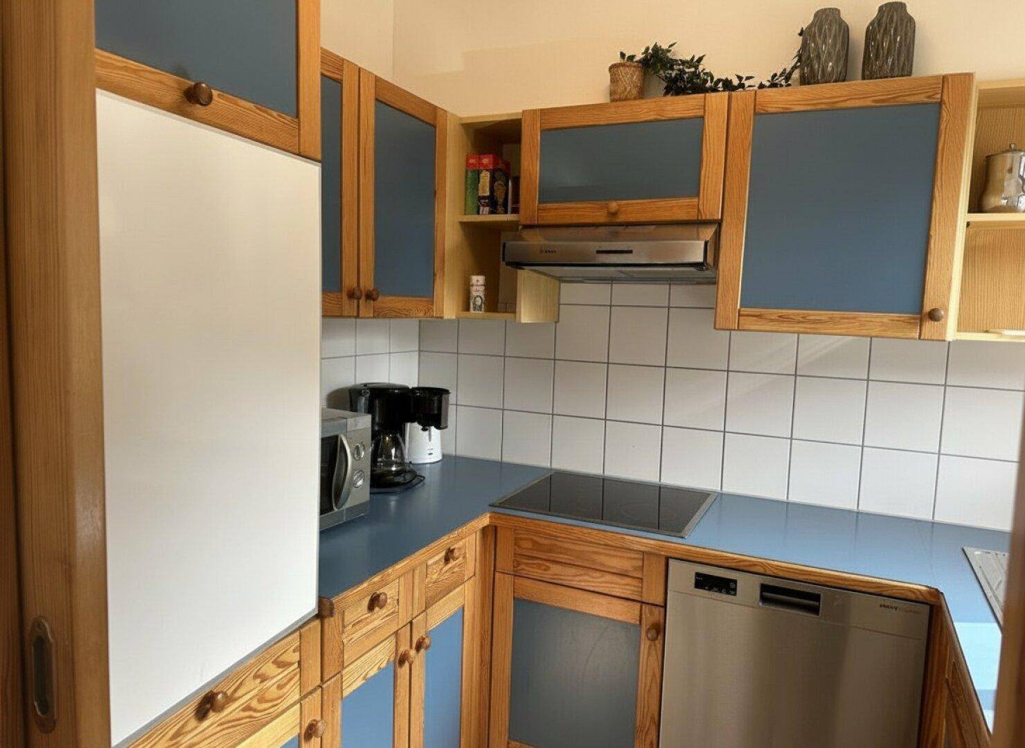 Gut ausgestattete Küche mit Induktionskochfeld, Dunstabzugshaube, Mikrowelle und Kaffeemaschine.