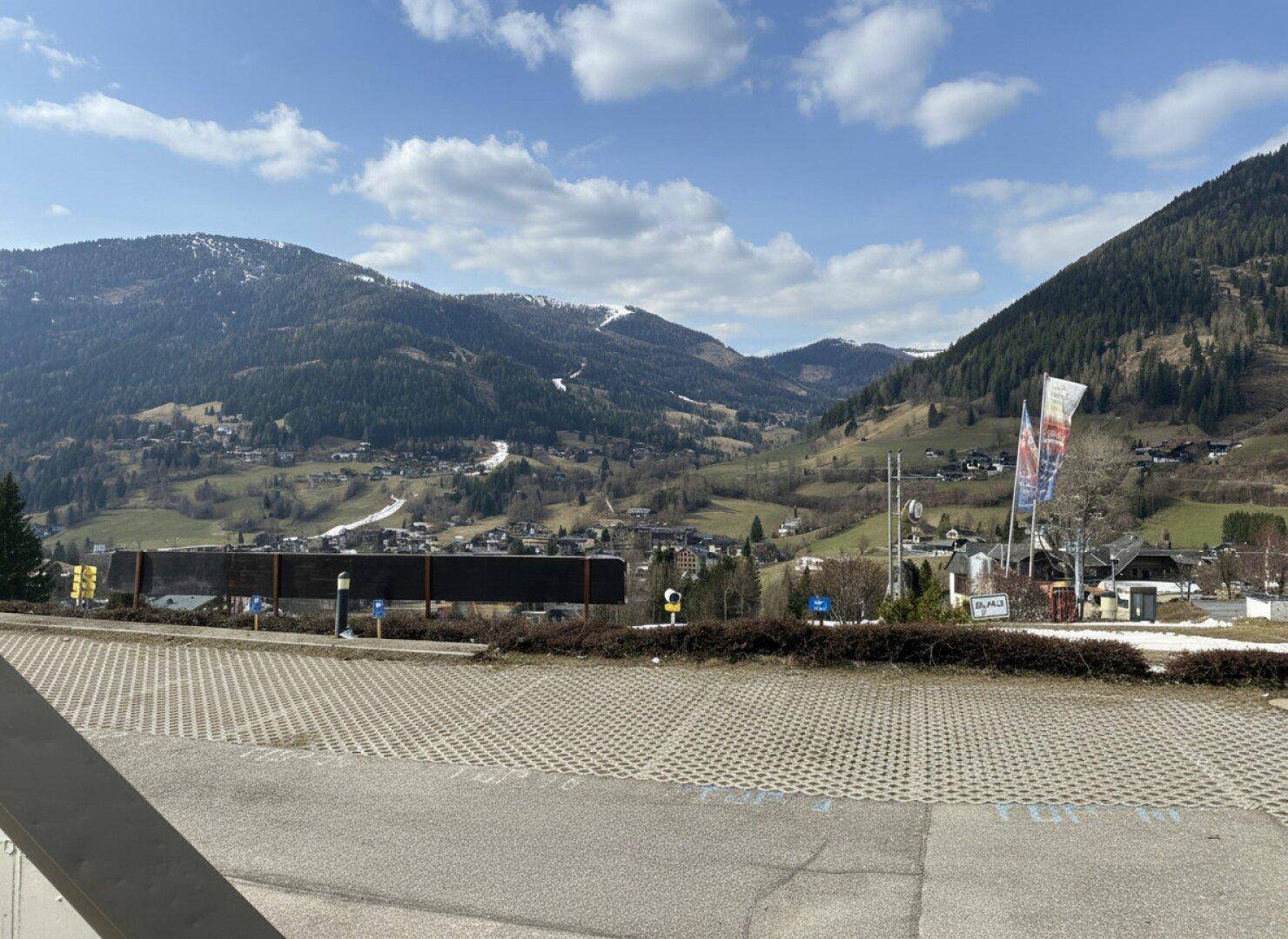 Weitläufiger Parkplatz mit Panoramablick auf die beeindruckende Bergwelt und das Tal.